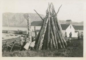 Image of Winter wood piled and children playing by one pole